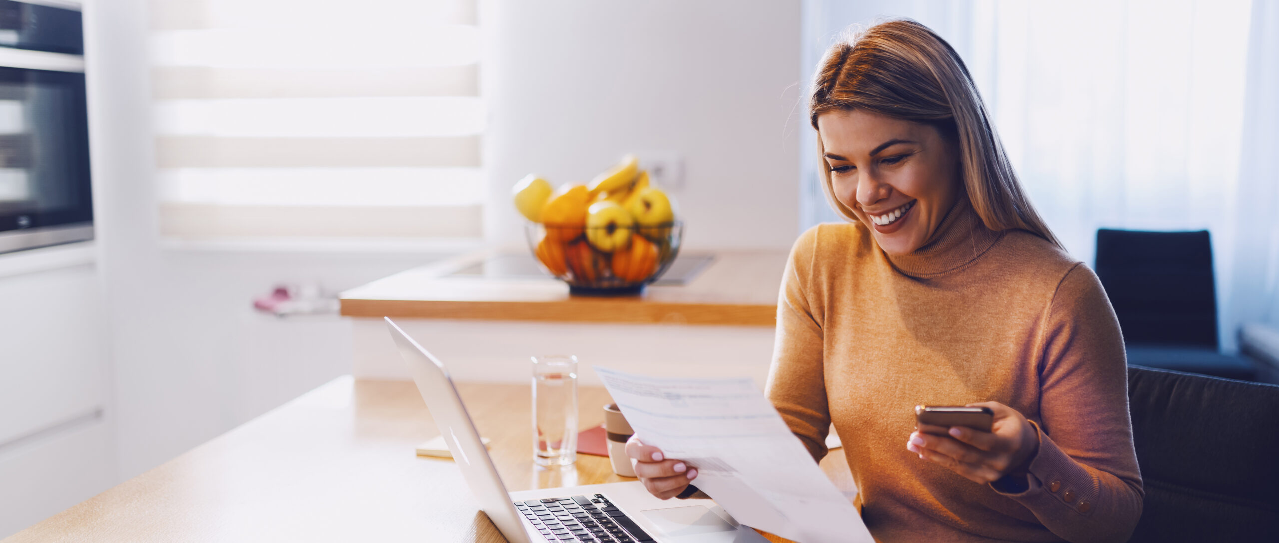 Image of woman, smiling, reviewing her light band bill while using a mobile device