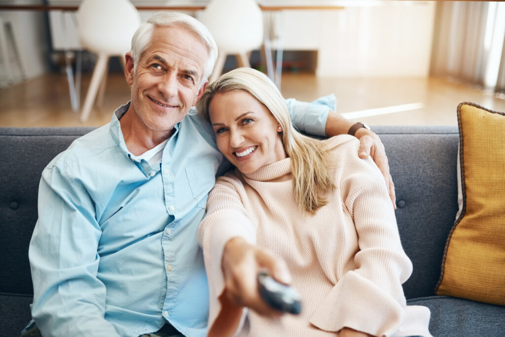 Image of older couple relaxing on sofa at home exploring CDE television services