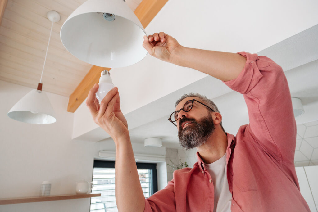 Image of man swapping out light bulbs with energy, efficient models