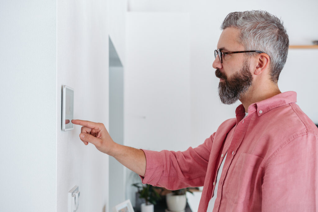 Image of man adjusting digital thermostat in home