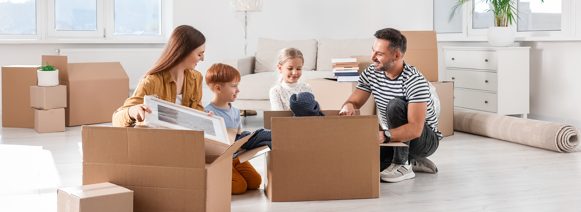 Happy family unpacking boxes in new apartment. Moving day - CDE stop service