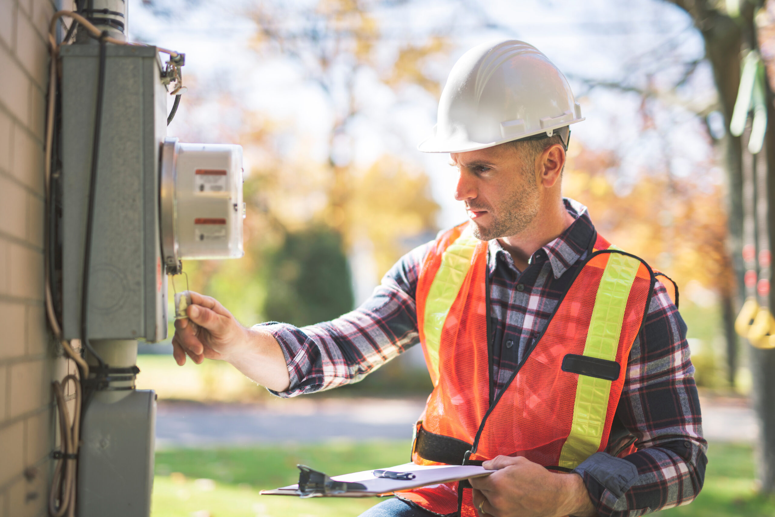 Utility worker analyzing reader, meter box with safety equipment on